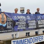 Die Stars kommen „at the beach“: das TSNT-Team mit dem Event-Plakat