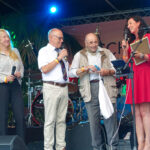 Ein Gast auf der Bühne, freundlich begrüßt von Bürgermeisterin Bärbel Schäfer (re), Bürgervorsteherin Renate Sonntag und Dorfvorstand MIchael Pätau (2.v.l.)