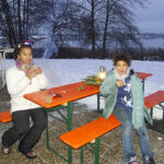 Gemütlich draußen sitzen mit Blick auf den See: Kinder und Eltern genießen die Stimmung beim Advents-Treff